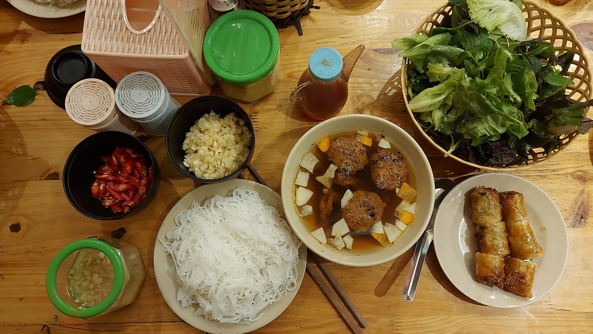 Bun cha with grilled pork patties, rice noodles, herbs and fried spring rolls