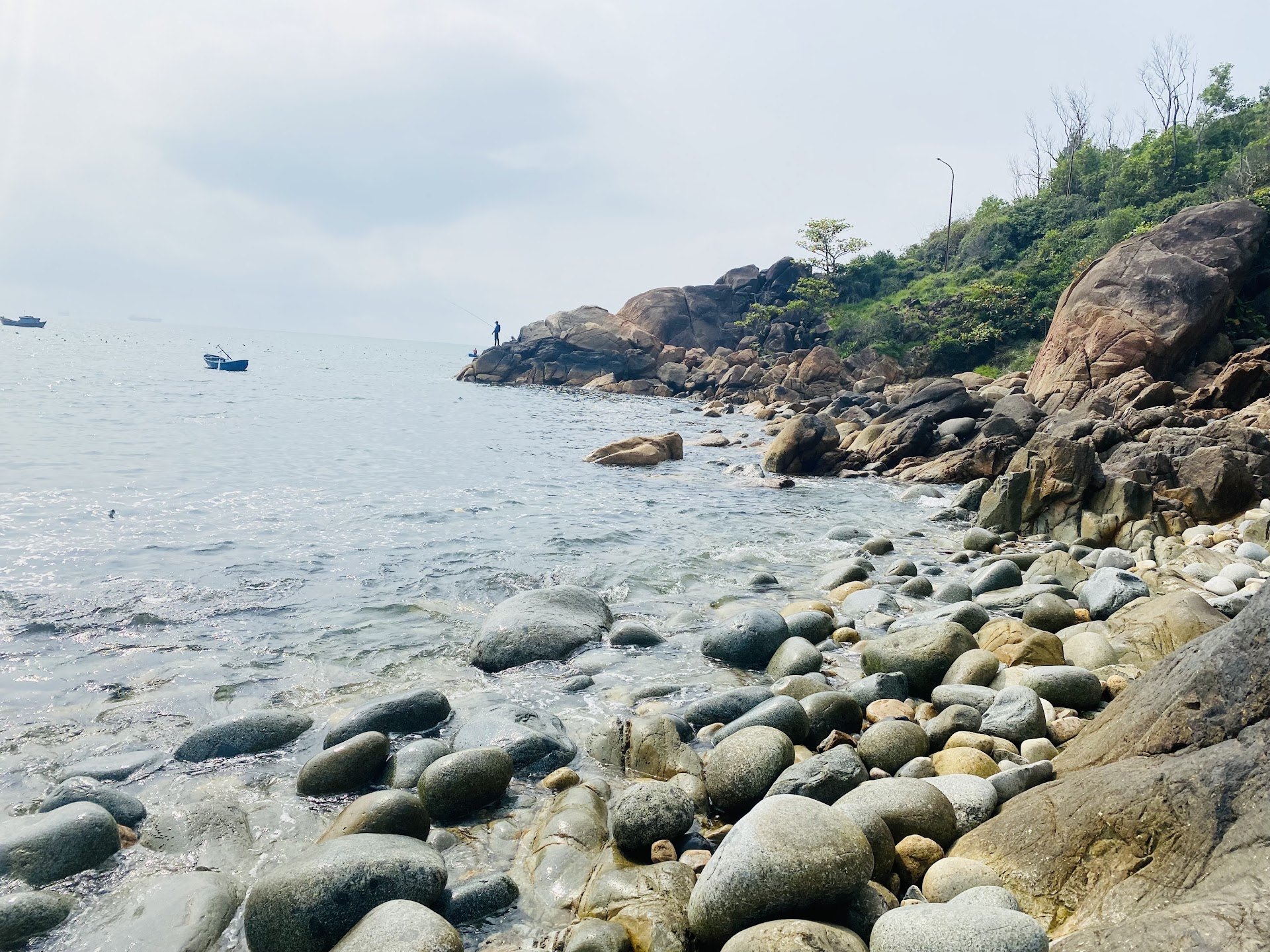 Round grey boulders and clear shallow water at Queen's Beach on Ghenh Rang headland