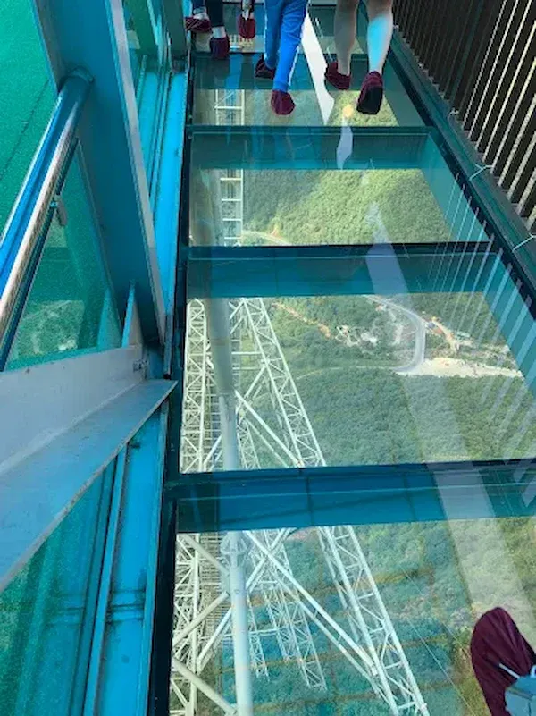 Looking Down Through Glass Floor Panels to the Steel Support Tower and Valley Road, Visitors With Red Protective Shoe Covers on  Rong May Glass Bridge of Sapa