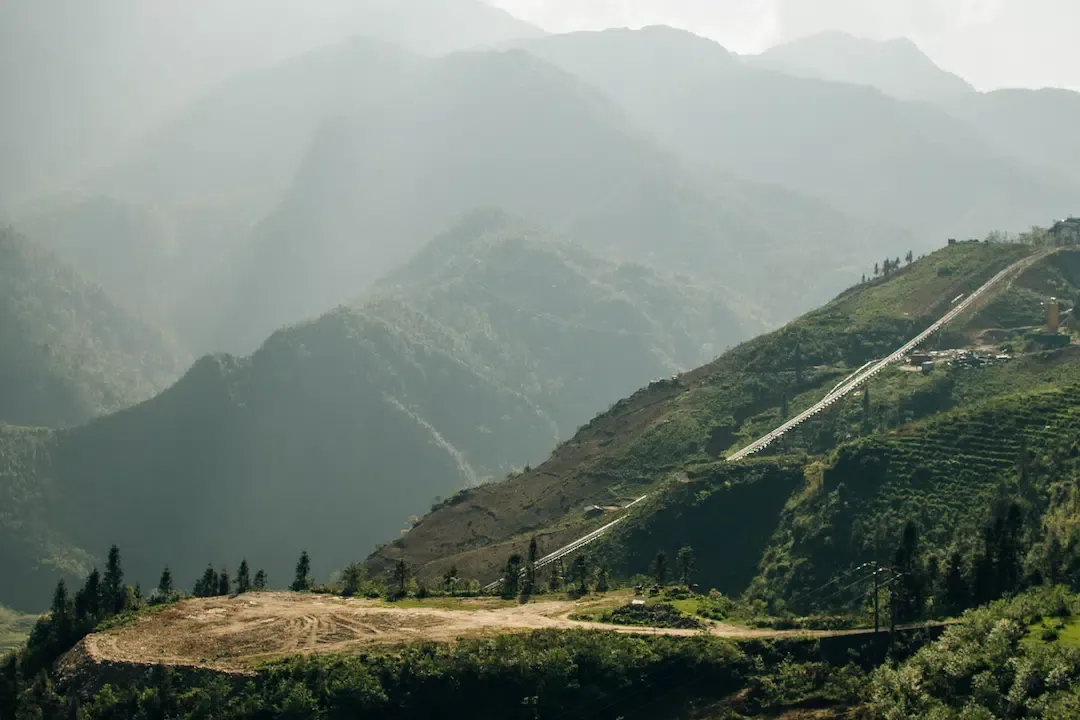 Vast green rice terraces carved into the steep hillsides of the Muong Hoa Valley near Sapa Vietnam with misty mountains in the distance