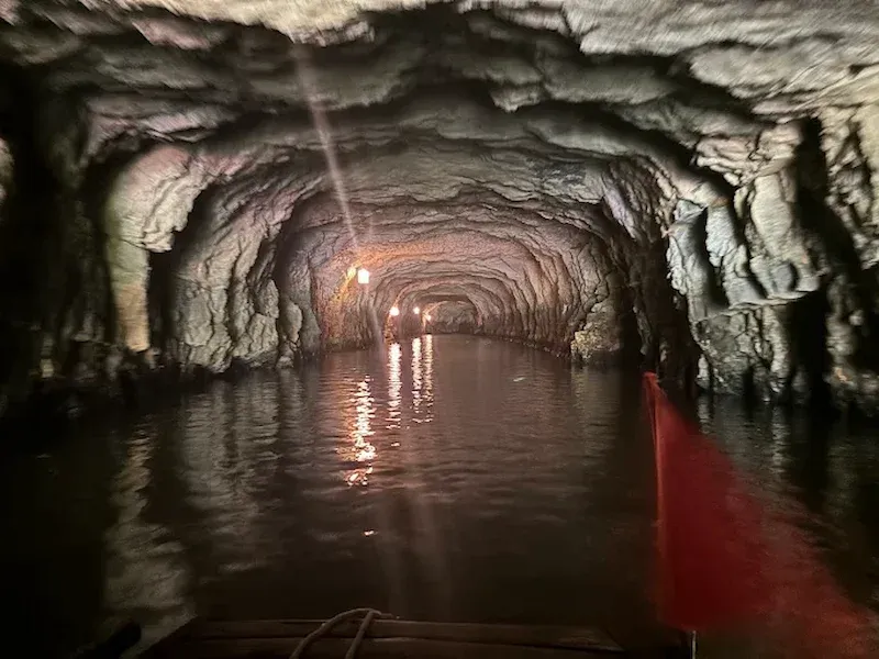Inside Trang An cave with stalactites and underground river reflections (Ninh Binh)