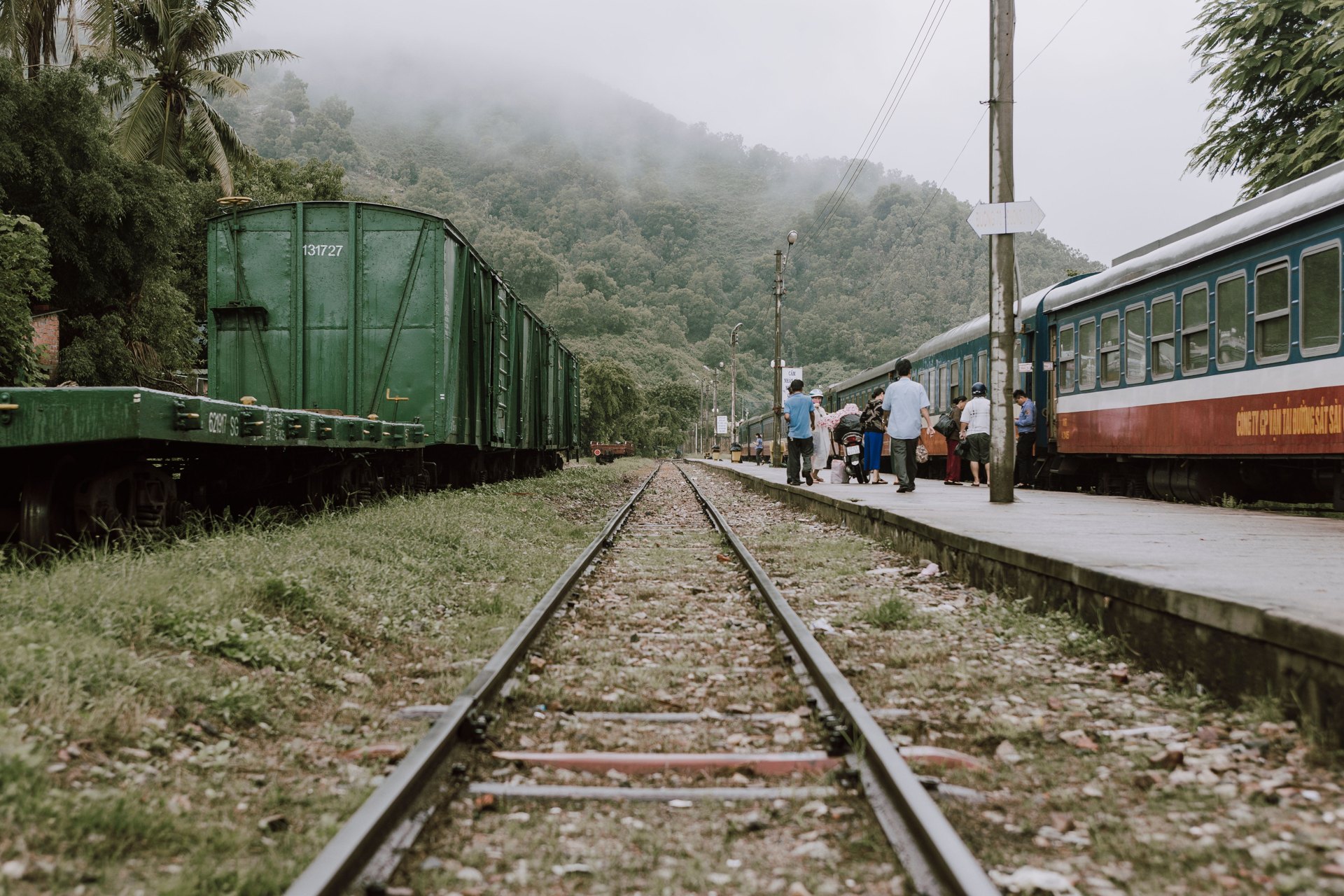 Passengers boarding a Vietnamese passenger train at a misty station platform
