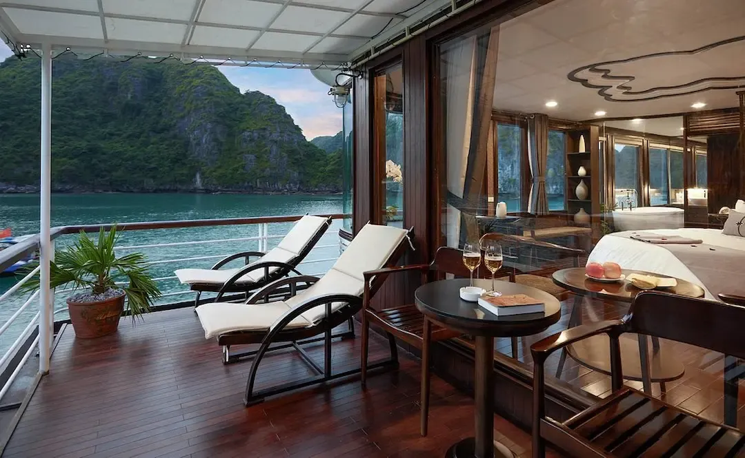 Premium Luxury Cruise Cabin at Bai Tu Long Bay With Private Terrace, Lounge Chairs, and Direct Views of Turquoise Water and Limestone Cliffs