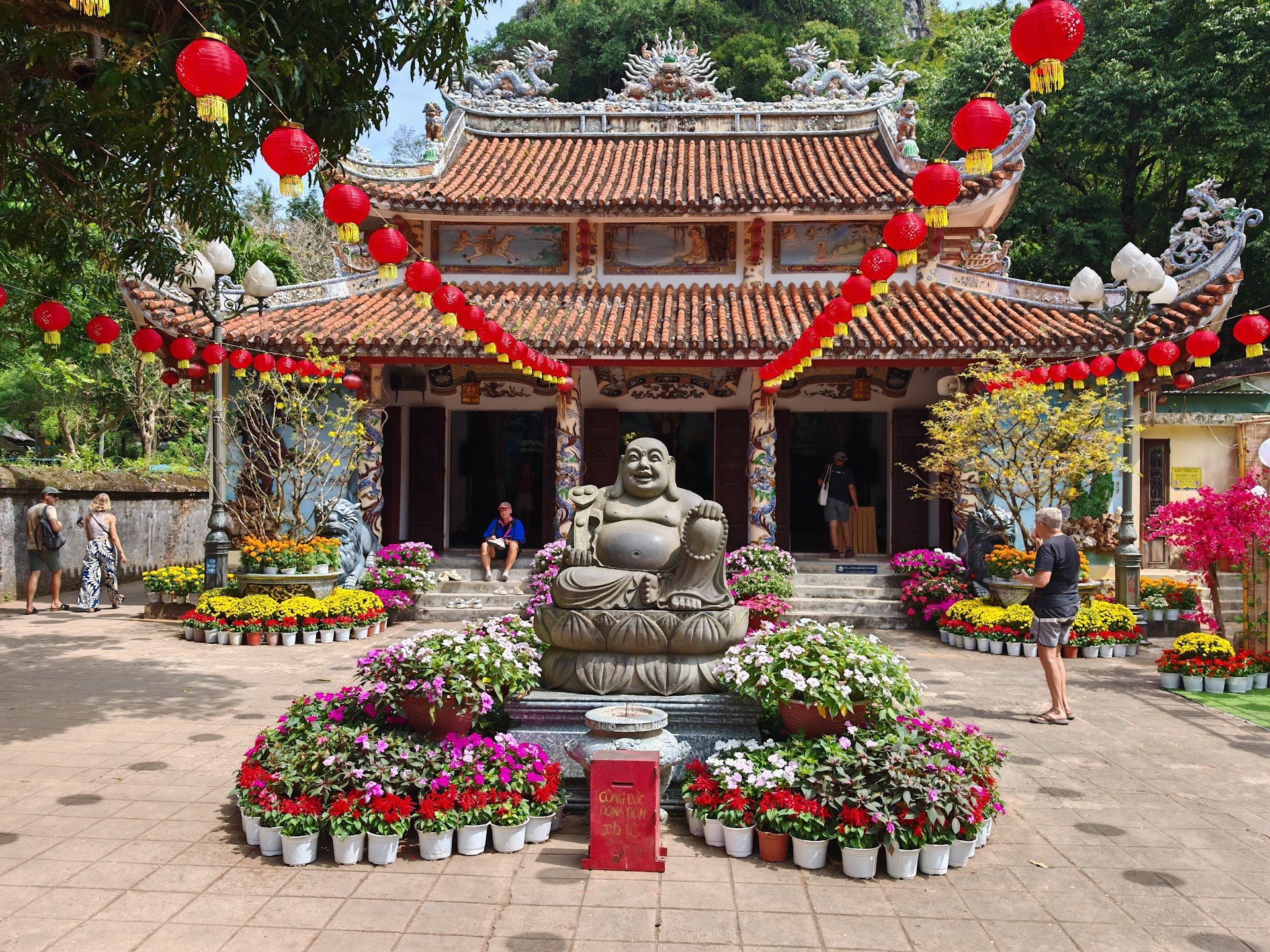 Temple courtyard with red lanterns and a seated statue at Marble Mountains