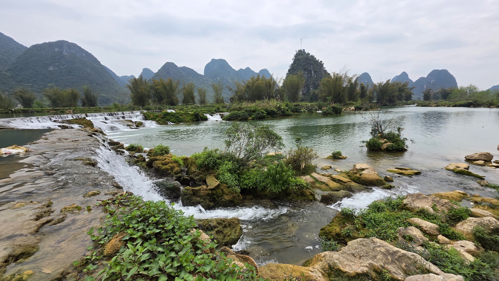 Small cascades and green islets on the Quay Son River with karst peaks behind