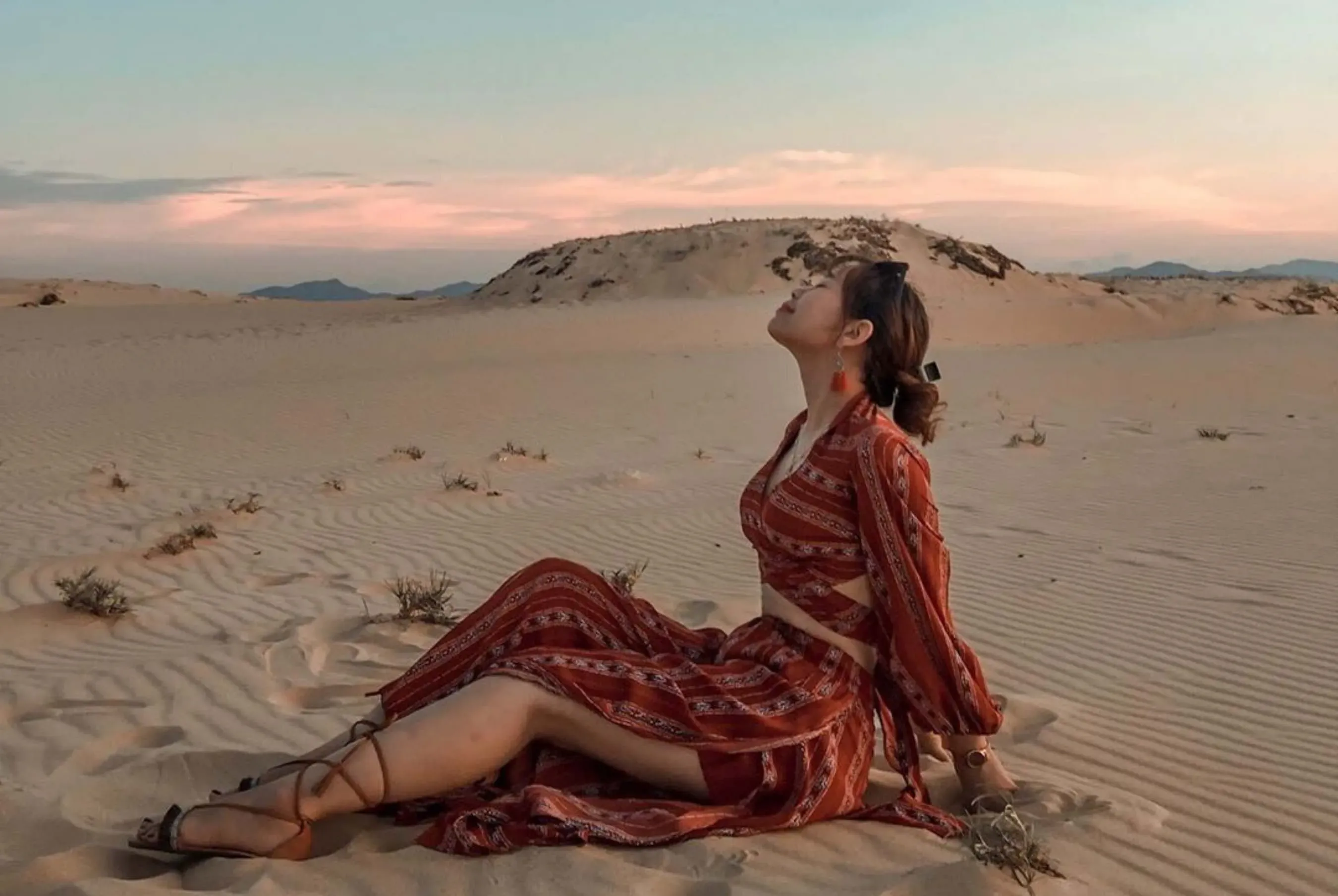 cô gái ngồi chụp hình giữa đồi cát quang phú