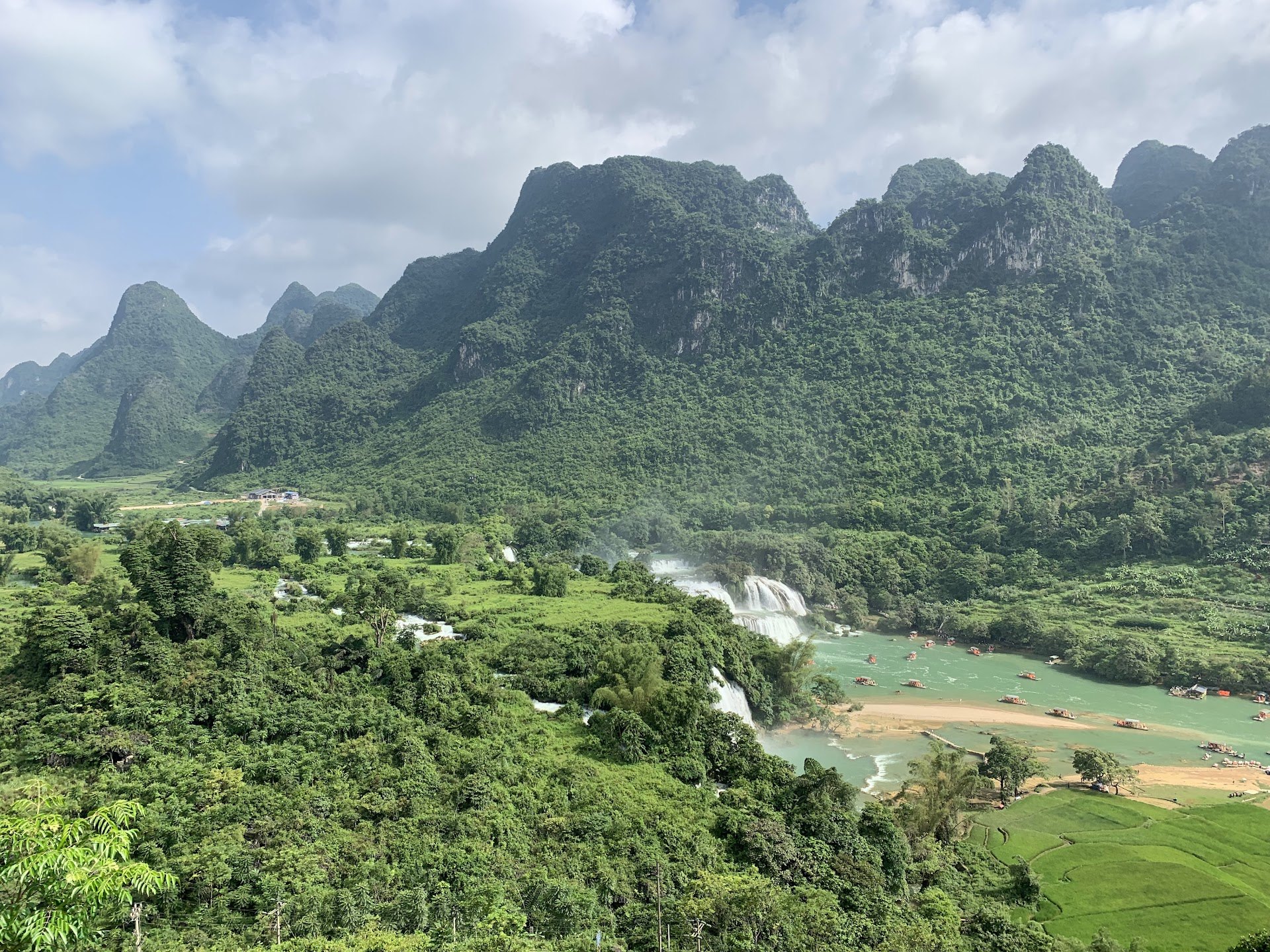 Ban Gioc Waterfall seen from the hillside, with rafts moored on the river below