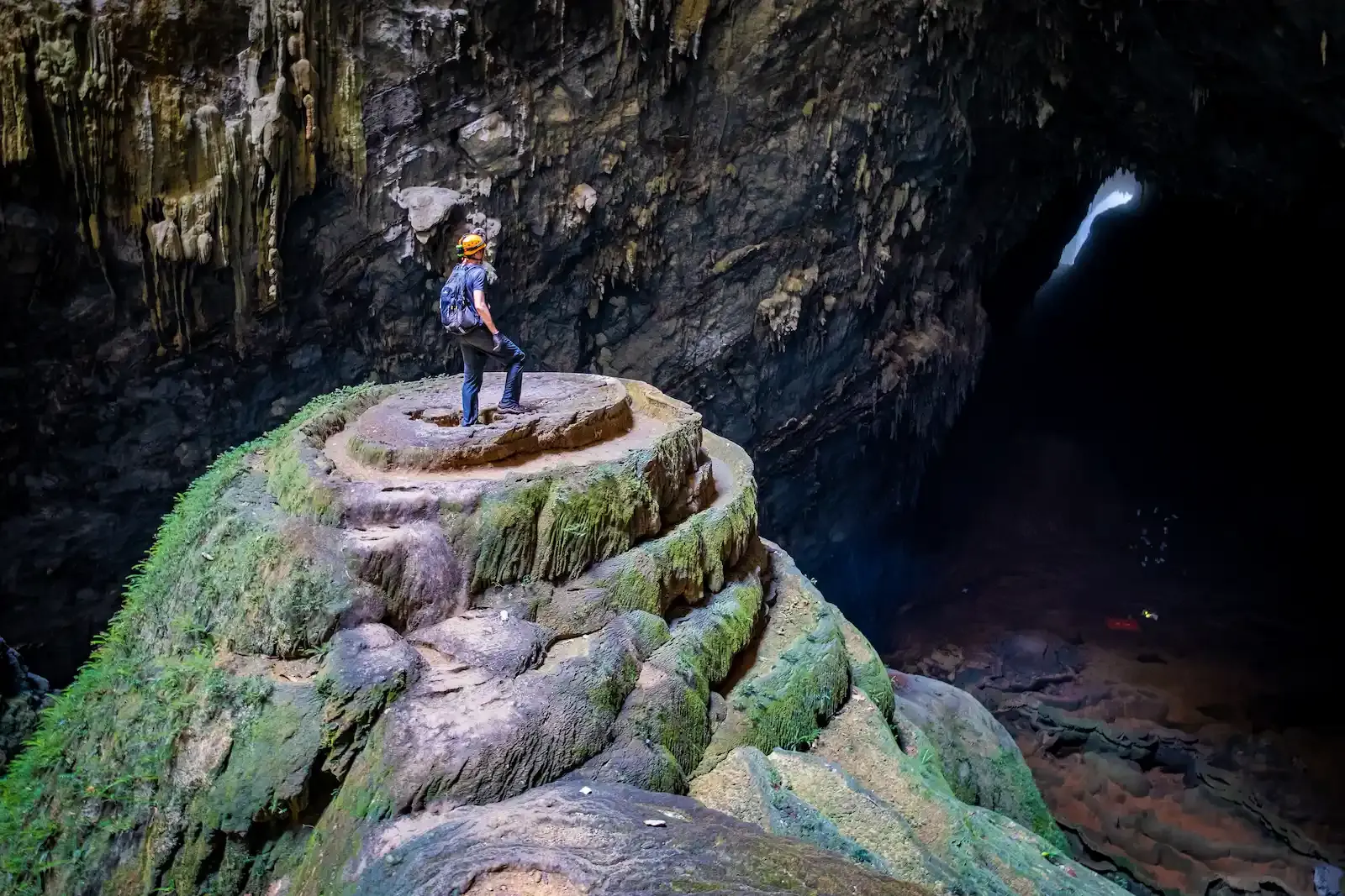 Solo explorer standing on moss covered limestone terraces inside Son Doong Cave near the famous Green Gours formation in Phong Nha Ke Bang Vietnam.