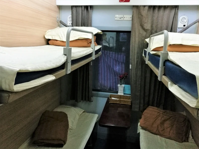Overnight train arriving at a small Vietnamese station platform at night