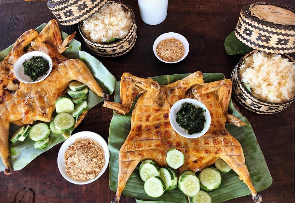 Grilled Chicken Dish Served on Banana Leaves With Sliced Cucumbers and Dipping Sauce, Accompanied by Sticky Rice in Woven Baskets, Showcasing a Traditional Phong Nha, Vietnam Special