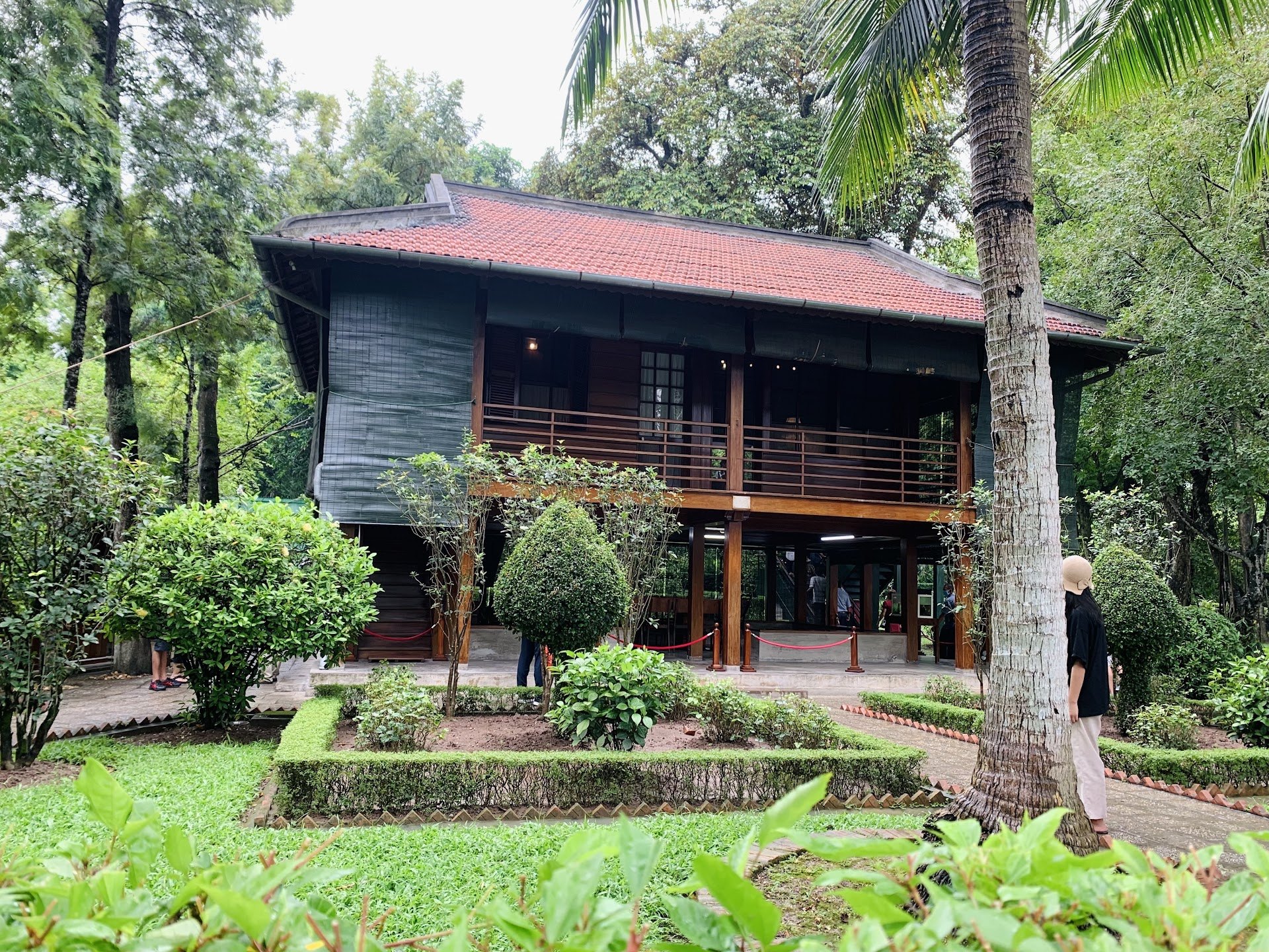 Ho Chi Minh's wooden stilt house among trees and clipped hedges in the Presidential Palace grounds