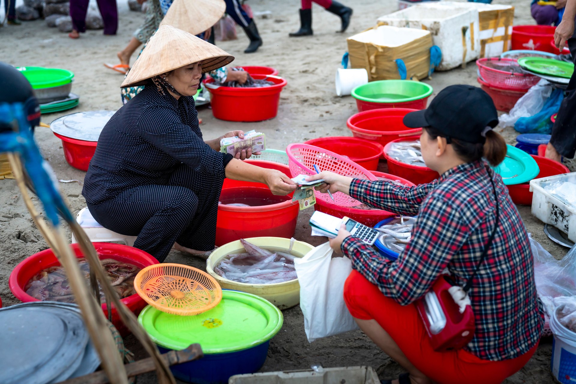 Market vendor in a conical hat paying a customer in dong notes