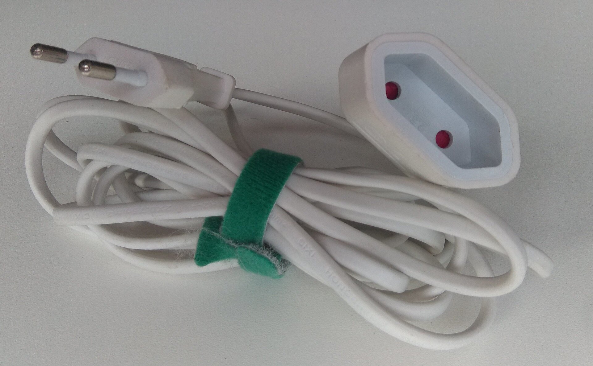 White two-pin Europlug and its extension socket on a coiled cable