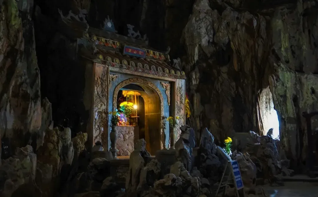 Huyen Khong Cave Da Nang with dramatic sunlight streaming through natural skylight illuminating Buddha statue and Buddhist shrine altar