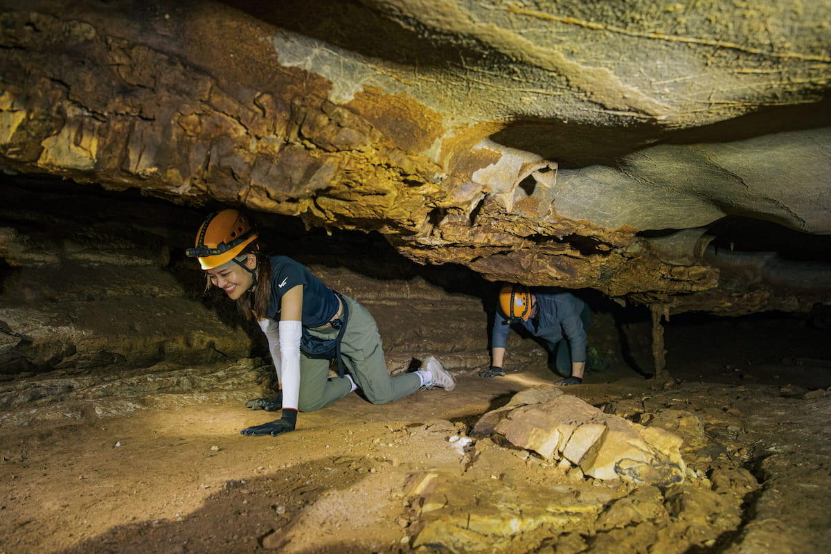 Group wading waist-deep through a lit cave passage in Phong Nha with head torches